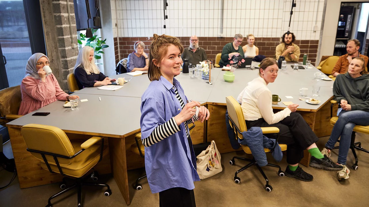 Oplægsholder og tilhørere som sidde rundt om et bord.